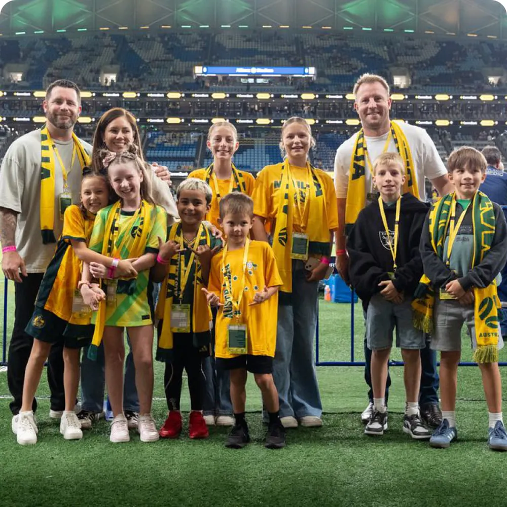 Fans in Matildas gear standing on the pitch before a match