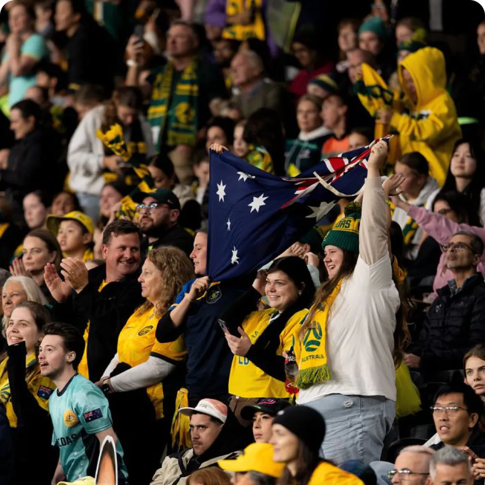 Matildas fans cheering in the stands with an Australian flag